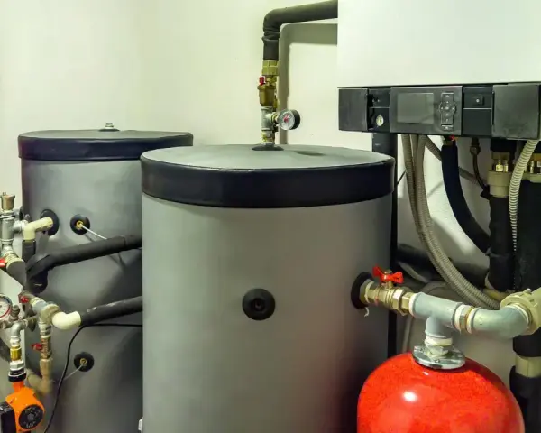 Installazione scaldabagno a pompa di calore con serbatoi grigi, serbatoio rosso e caldaia bianca.