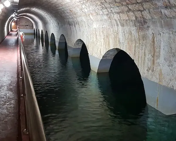 Interior de aljibes de agua abovedados, con arcos que se sumergen en el agua. Un pasillo con barandilla recorre el lateral.