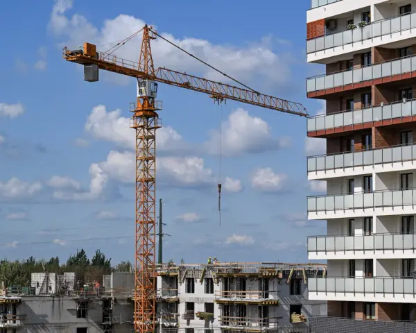 Plac budowy, gdzie lex deweloper wznosi nowoczesne apartamenty. Widoczny dźwig budowlany i postępujące prace.