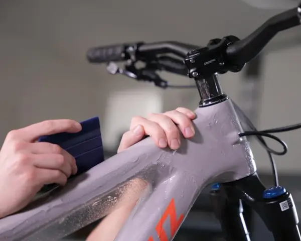 Hands apply protective film to a mountain bike frame. This bike is ready for any terrain, whether trails or roads.