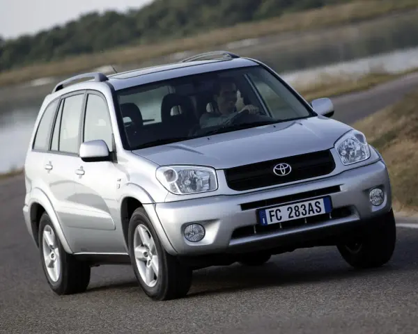 Srebrny SUV Toyota RAV4 na drodze, z kierowcą za kierownicą.