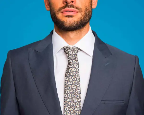 Uomo con abito blu, camicia bianca e cravatta fantasia. Un abbinamento classico per un look elegante.