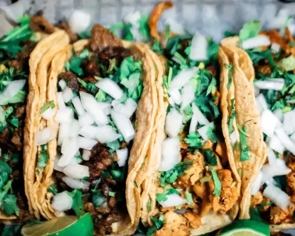 Fünf köstliche Tacos mit Rindfleisch und Hähnchen, garniert mit Zwiebeln und Koriander. Perfekt für einen Taco-Abend!