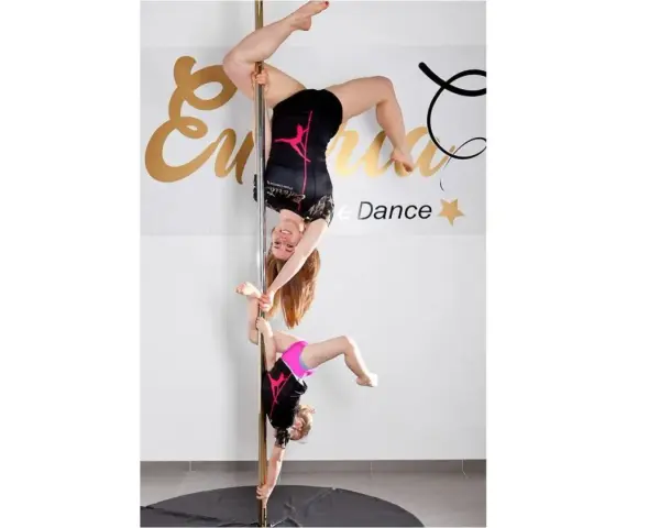 Dwie tancerki, dorosła i dziecko, wykonują akrobacje na słupie. To dowód, że pole dance dla dzieci to świetna zabawa i aktywność.