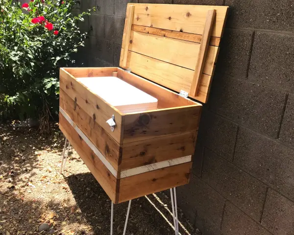 Wooden DIY deck box with lid open, showing white interior, on hairpin legs.