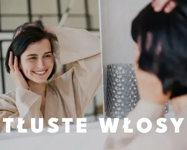Uśmiechnięta kobieta dotyka swoich włosów, zastanawiając się, co zrobić, żeby włosy się nie przetłuszczały.