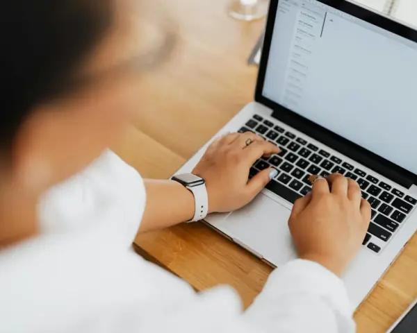 Kobieta pisze na laptopie, na ekranie widać artykuł po niemiecku.