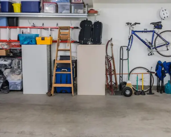 Garage med cykel, stegar, förvaringslådor och en liten fönsterlucka för ventilation.