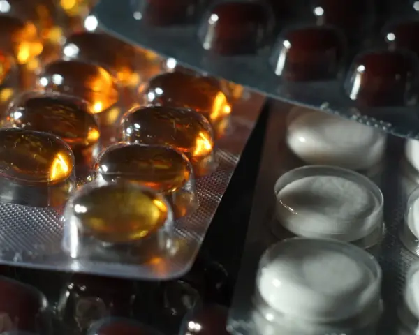 Närbild på flera blisterförpackningar med piller. En förpackning innehåller gulaktiga kapslar, en annan vita tabletter och en tredje mörkbruna piller. Kanske en av dem innehåller folic acid svenska.