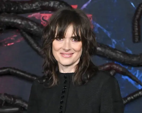 Winona Ryder, gwiazda filmów i seriali, w tym "Stranger Things", na tle dekoracji z mackami i logo Netflix.