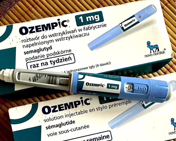Dwa opakowania i dwa peny leku Ozempic 1 mg na podkładce bambusowej.