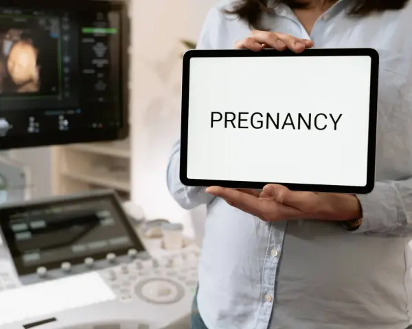 Wczesna ciąża, 2 tydzień. USG pokazuje zarodek, a na tablecie widnieje napis "PREGNANCY".
