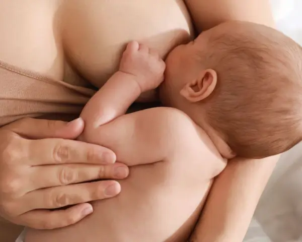 Un neonato si nutre al seno, ricevendo il prezioso colostro, un dono naturale per la sua crescita.