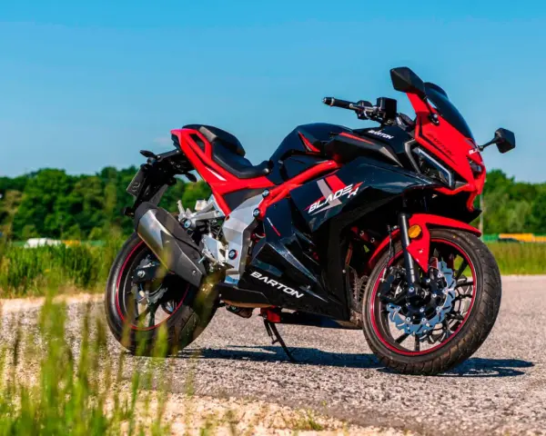 Czarny sportowy motocykl Barton Blade R 125 V Max z czerwonymi akcentami, zaparkowany na drodze w słoneczny dzień.