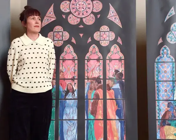 Une femme pose devant des vitraux stylisés, évoquant les vitraux de Notre Dame. Les scènes colorées représentent des figures humaines et des motifs floraux.