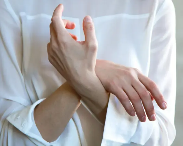 En person håller sin handled, möjligen på grund av inflammation i senskidan.