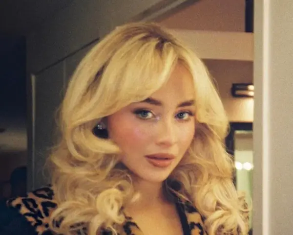 Frau mit voluminösem blondem Haar und Leopardenmuster-Jacke.