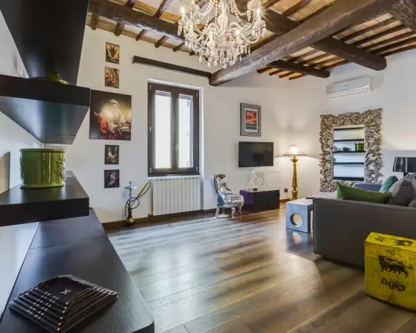 Soggiorno con travi a vista, lampadario di cristallo e un tocco di stile rustico.