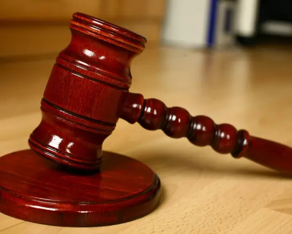 Młotek sędziowski na drewnianym stole. Symbolizuje sprzedaż mieszkania z wpisem komorniczym i decyzje prawne.