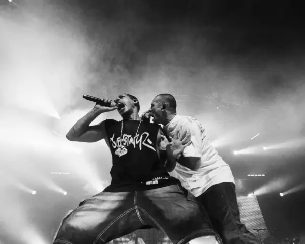 Deux rappeurs en pleine performance, l'un tenant un micro, l'autre le soutenant. Une scène intense qui illustre la puissance du hip hop en France.