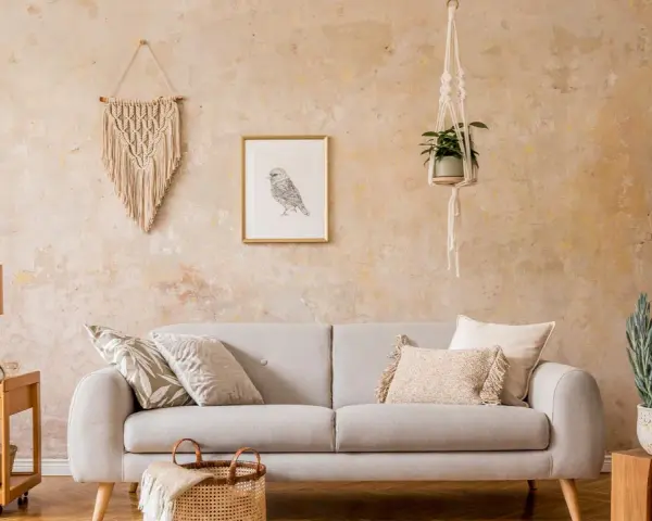 Gemütliches Wohnzimmer mit beiger Wischtechnik Wand, Sofa, Makramee-Deko und Pflanzen.