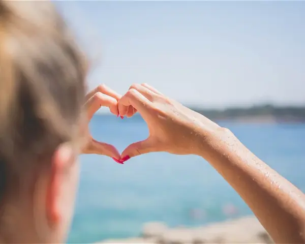 Message après premier rendez-vous avec un homme : un cœur formé par des mains mouillées sur fond de mer bleue.