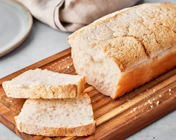Ein Laib japanisches Reisbrot, aufgeschnitten auf einem Holzbrett. Dieses Rezept für japanisches Reisbrot ist perfekt für alle, die glutenfreies Brot lieben.