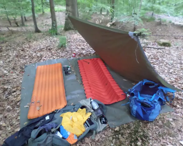 Zwei Isomatten, ein Tarp und Rucksäcke liegen bereit, um unter freiem Himmel zu schlafen.