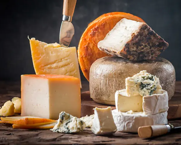 Kuski najlepsze sery: parmezan, pleśniowy, camembert i inne, ułożone na drewnianej desce.