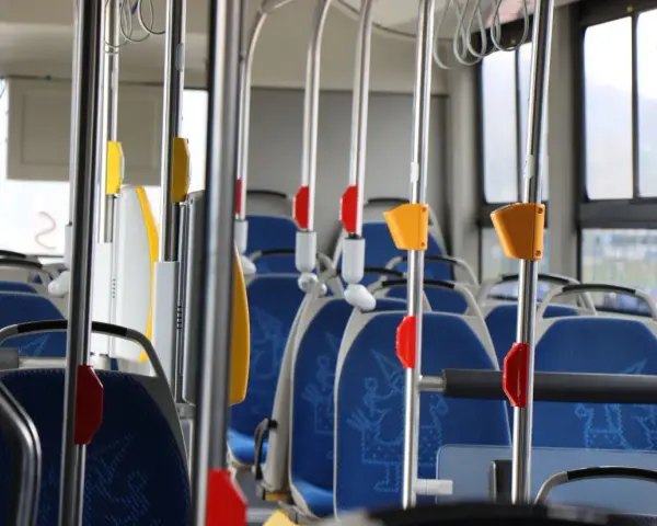 Wnętrze autobusu 139 z niebieskimi siedzeniami i metalowymi poręczami.