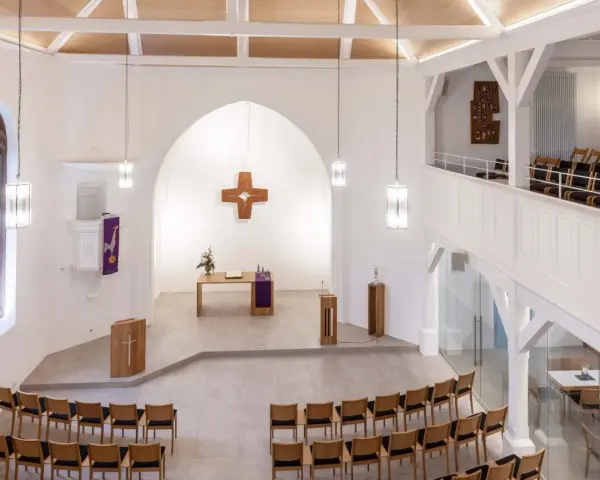 Moderner Aufbau evangelische Kirche mit Holzkreuz, Altar, Kanzel und vielen Sitzplätzen.