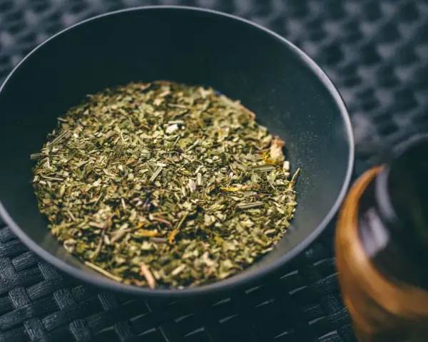 Suszone liście yerba mate w czarnej miseczce, gotowe do zaparzenia. To naturalny napój pobudzający.