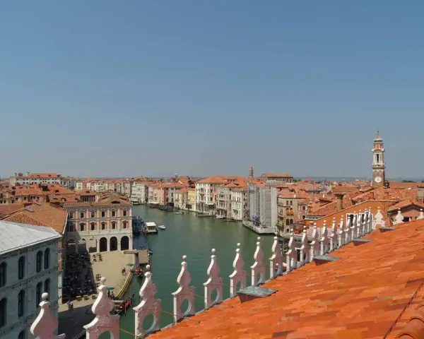 Vista dall'alto dei tetti rossi di Venezia, con il Canal Grande e le sue calli animate.