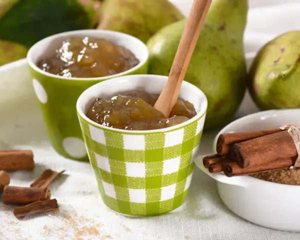Due tazze con **marmellata di pere** fatta in casa, pere fresche, cannella e zucchero di canna.