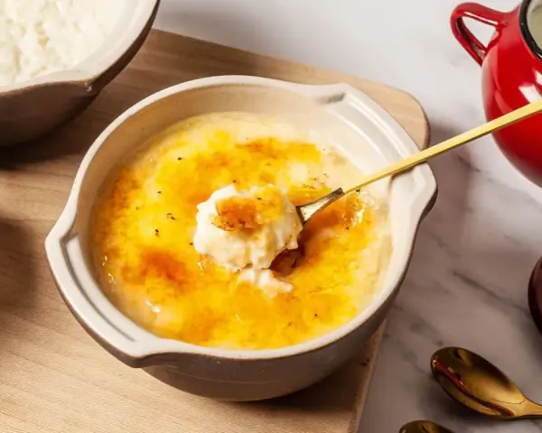 Delicioso arroz con leche asturiano con una capa crujiente de caramelo. Una cuchara dorada levanta una porción cremosa.