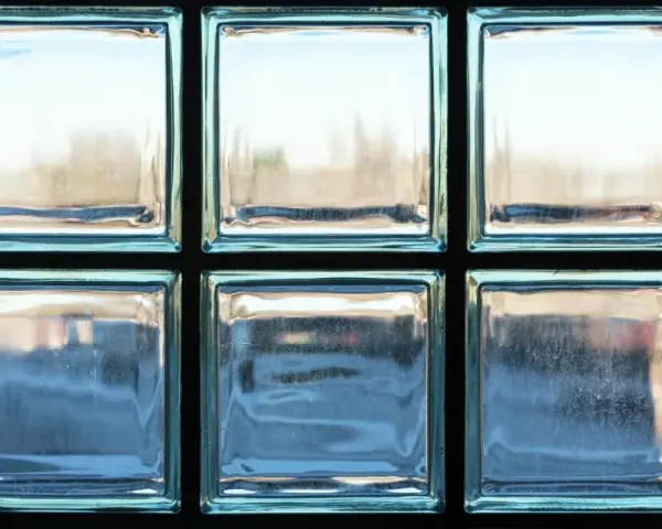 Un mur en brique de verre, reflétant la lumière extérieure, crée une ambiance douce et diffuse.