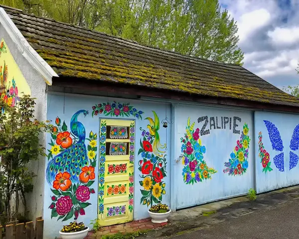 Kolorowy paw i kwiaty zdobią budynek w Zalipiu. Warto wybrać się na zwiedzanie tego malowniczego miejsca.