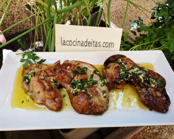Delicioso hígado de rape a la plancha con ajo y perejil, servido en una bandeja blanca.
