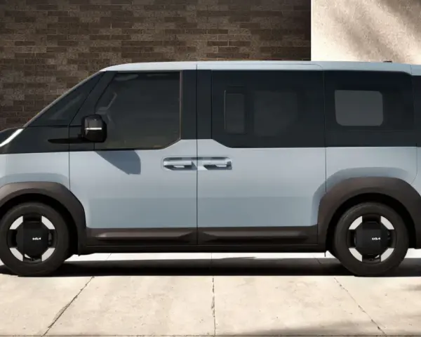 Jasnoszary elektryczny van Kia PV5 z czarnymi akcentami, widziany z boku.
