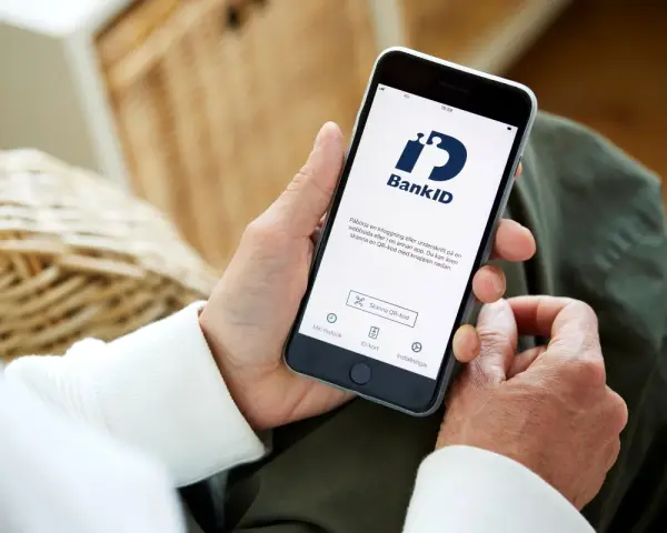 Person använder sin smartphone med BankID-appen för att logga in eller signera.