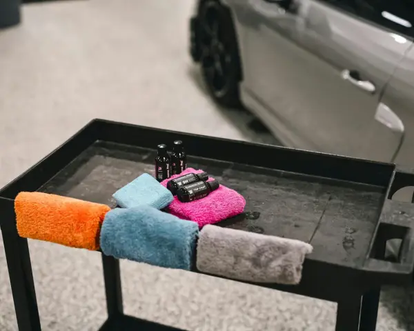 Kolorowe mikrofibry i buteleczki z preparatami do pielęgnacji auta. Tak prac mikrofibry, by auto lśniło.