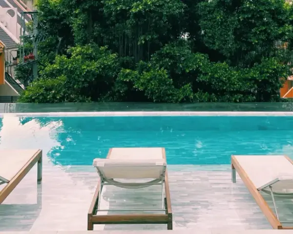 Piscina con lettini e vegetazione lussureggiante, un'oasi perfetta per sapere dove dormire a Bangkok.