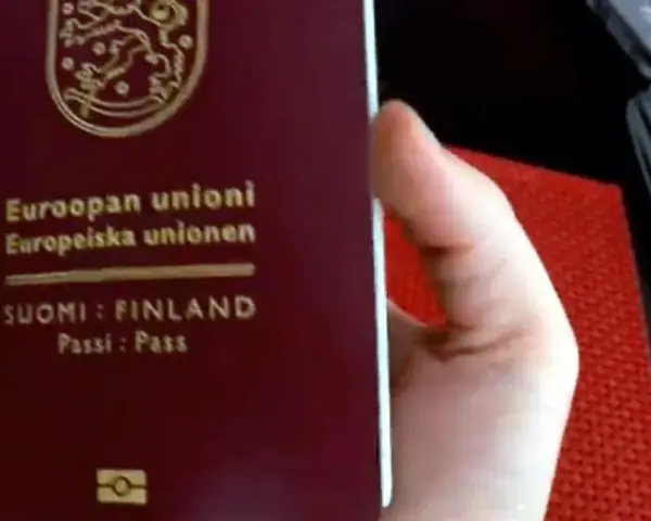 Dłoń trzyma paszport Finlandii. Czy do Finlandii trzeba mieć paszport? Tak, jeśli nie jesteś obywatelem UE/Schengen.