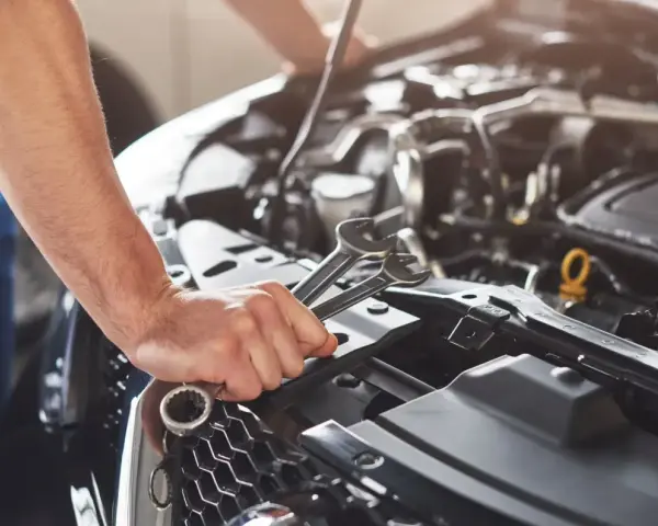 Mechanik sprawdza objawy awarii pompy paliwa Audi A4 B6 1.8T. W dłoni trzyma klucze.