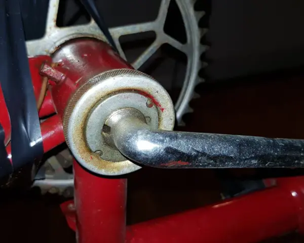 När man ska byta vevlager på cykeln syns en del av vevarmen och kedjekransen. Svart tejp håller ihop delar.