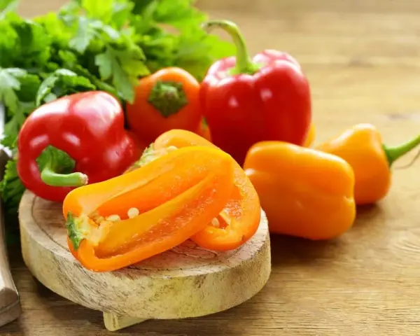 Peperoni piccoli colorati, pronti per gustose ricette. Un coltello e prezzemolo completano la scena.