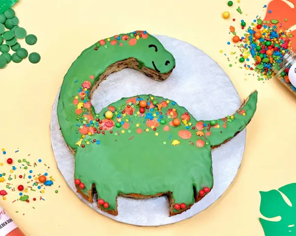 Grüne Dinosaurier Torte selber machen: Ein süßer Dino mit bunten Streuseln und Schokodrops. Perfekt für kleine Entdecker!