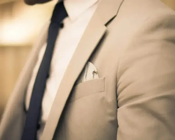 Elegancki mężczyzna w jasnej marynarce i granatowym krawacie. Zastanawiasz się, ile zarabia manager hotelu?