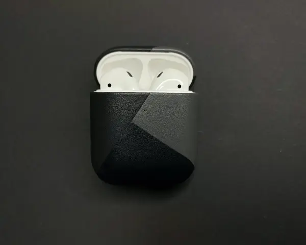 AirPods in einer schwarzen Hülle mit grauem geometrischem Muster.