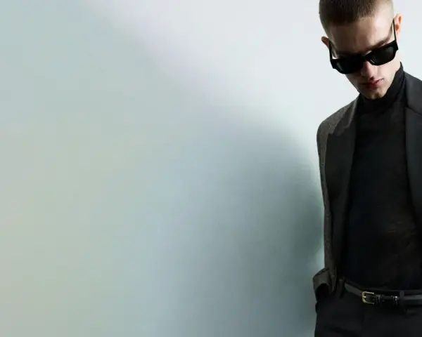 Joven con gafas de sol y traje elegante, listo para una **nochevieja en casa** con estilo.